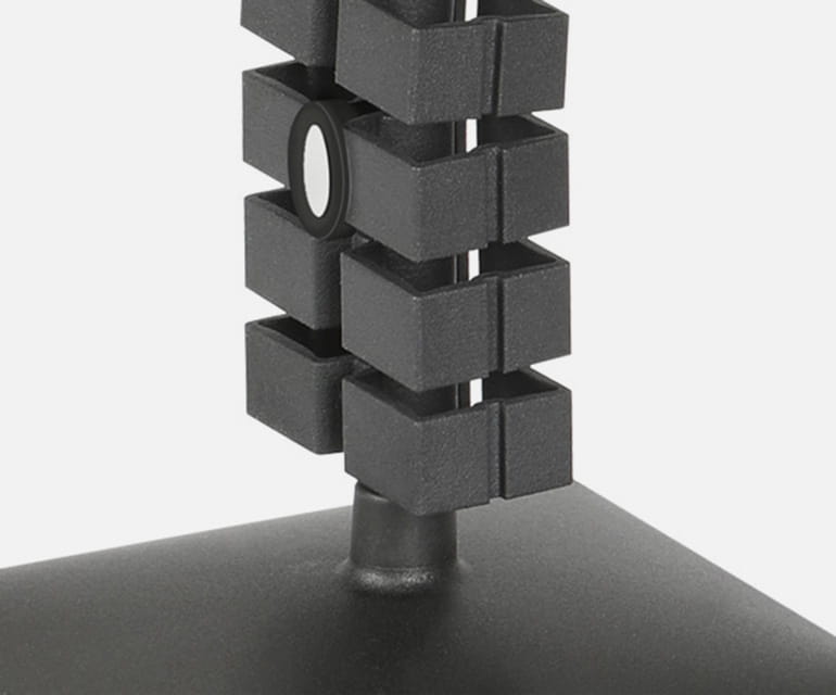 Gros plan sur une spirale de câble noire avec des segments carrés pour une gestion ordonnée des câbles, fixée à une base.