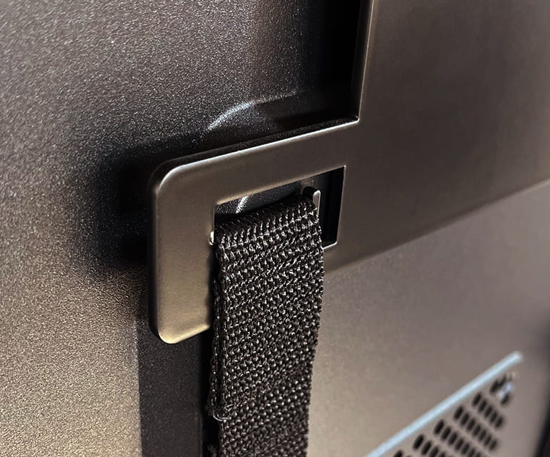 Gros plan sur une sangle de fixation noire solidement passée à travers un support en métal sur un ordinateur de bureau.