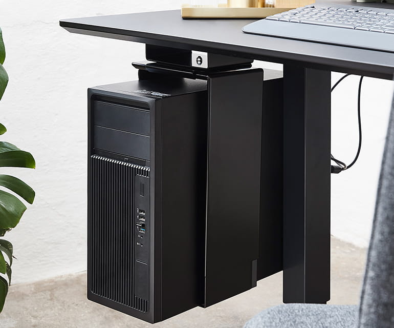 Bureau assis-debout moderne avec un plateau noir, doté d’un support PC monté sous le bureau, tenant solidement un ordinateur de bureau.