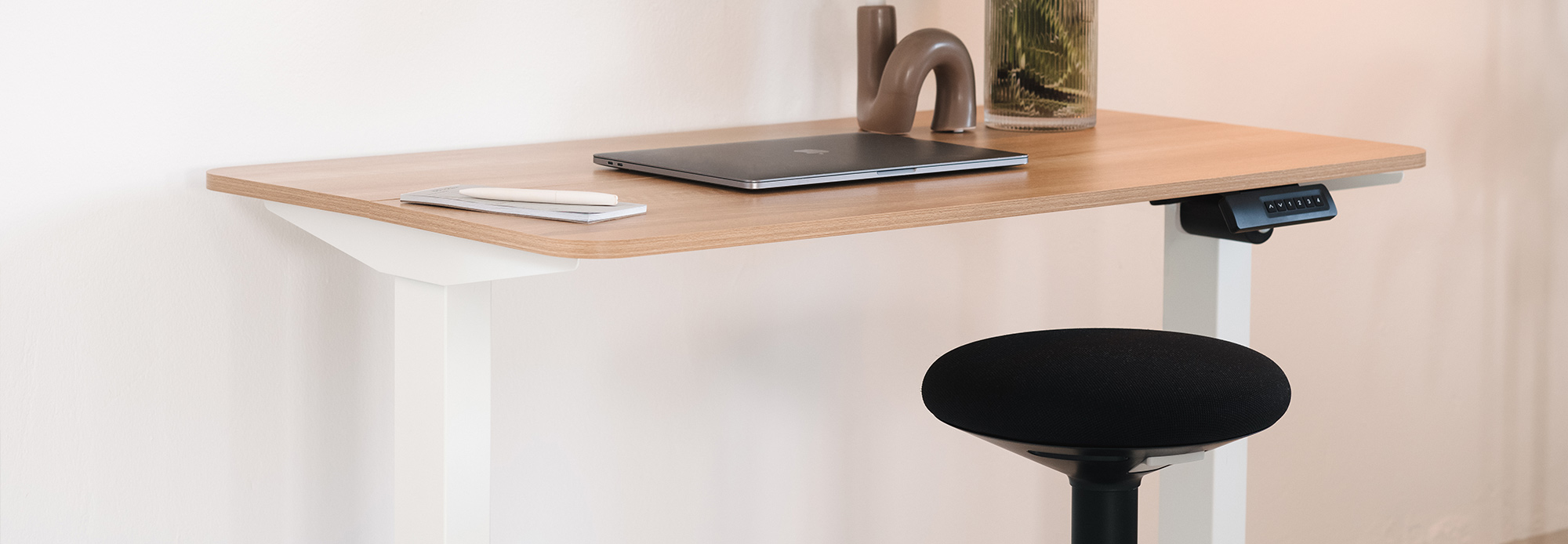 Höhenverstellbarer Tisch mit Holzplatte, Laptop, Smartphone und Steh-Sitzhilfe (Stehhocker), Bedienelement für Höhenverstellung unter dem Tisch.