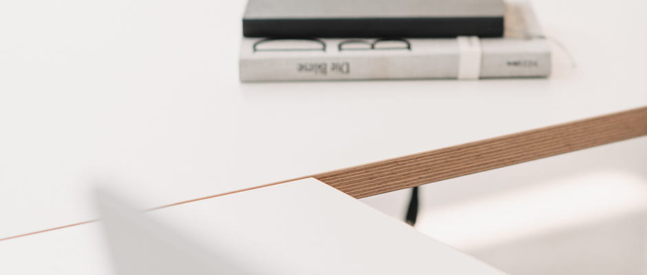 Minimalistischer Arbeitsplatz mit Büchern auf einem nachhaltigen Holztisch, fokussiert auf Materialtextur.