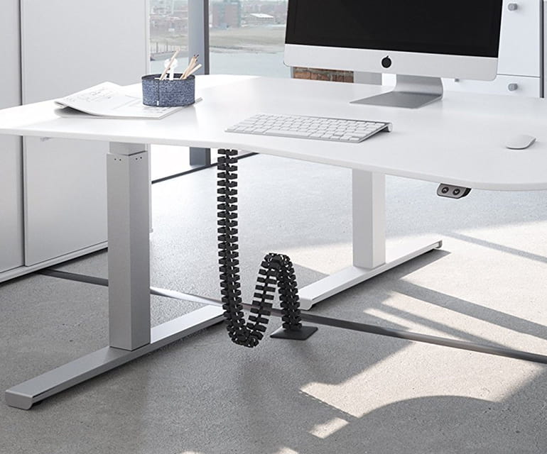Bureau assis-debout moderne avec un plateau blanc, doté d’une spirale de câble noire pour une gestion ordonnée des câbles et un poste informatique.