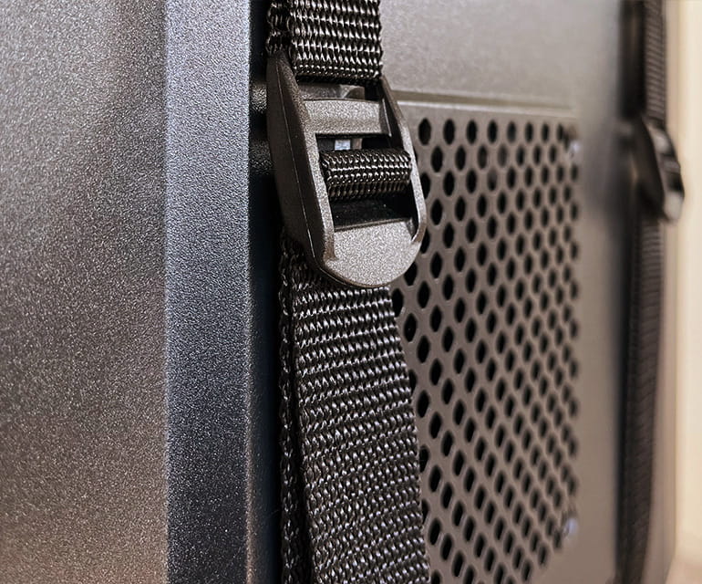 Gros plan sur un ordinateur de bureau solidement fixé à un support PC à l’aide de sangles noires robustes.