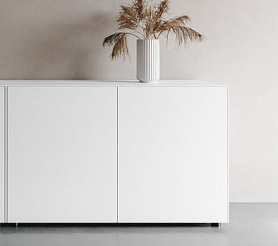 Weißes Sideboard in minimalistischem Design mit einer Vase und Trockenblumen darauf.